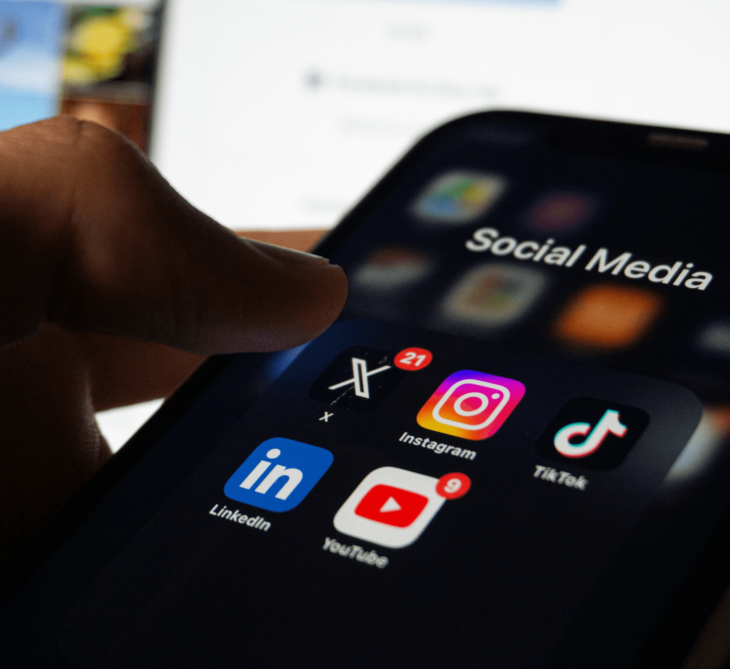 Tela de celular projeta o logotipo de diferentes redes sociais: Instagram, X, TikTok, LinkedIn e YouTube